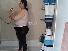 Vuxen, vacker och fet kvinna tar en våt dusch i vit tanktop och svarta leggings