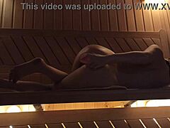 Młoda kobieta bawi się różowym dildo w saunie, doświadczając orgazmu