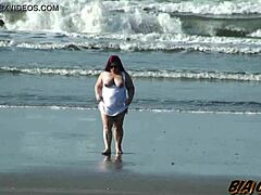 الأم الممتلئة الجسم تعرض أصولها على الشاطئ بأشعة الشمس الرائعة